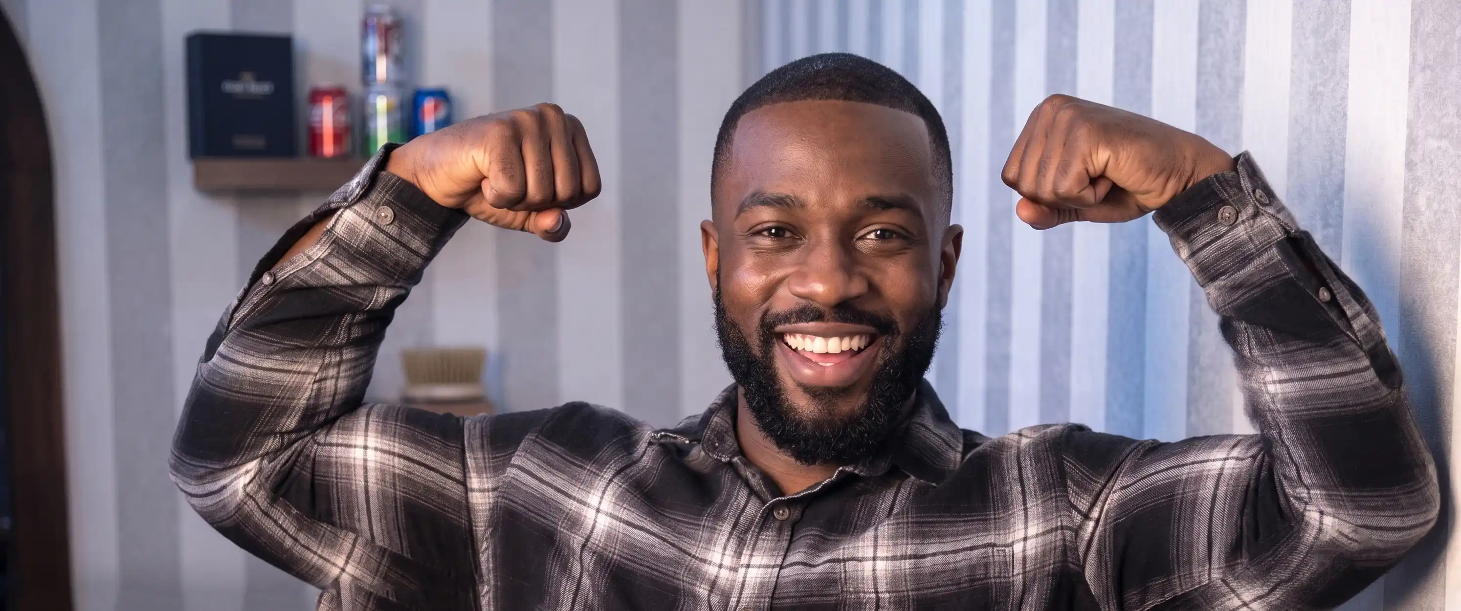 Confident smiling African American gentleman flexing bicep after successful Afro Hair Transplant restoration
